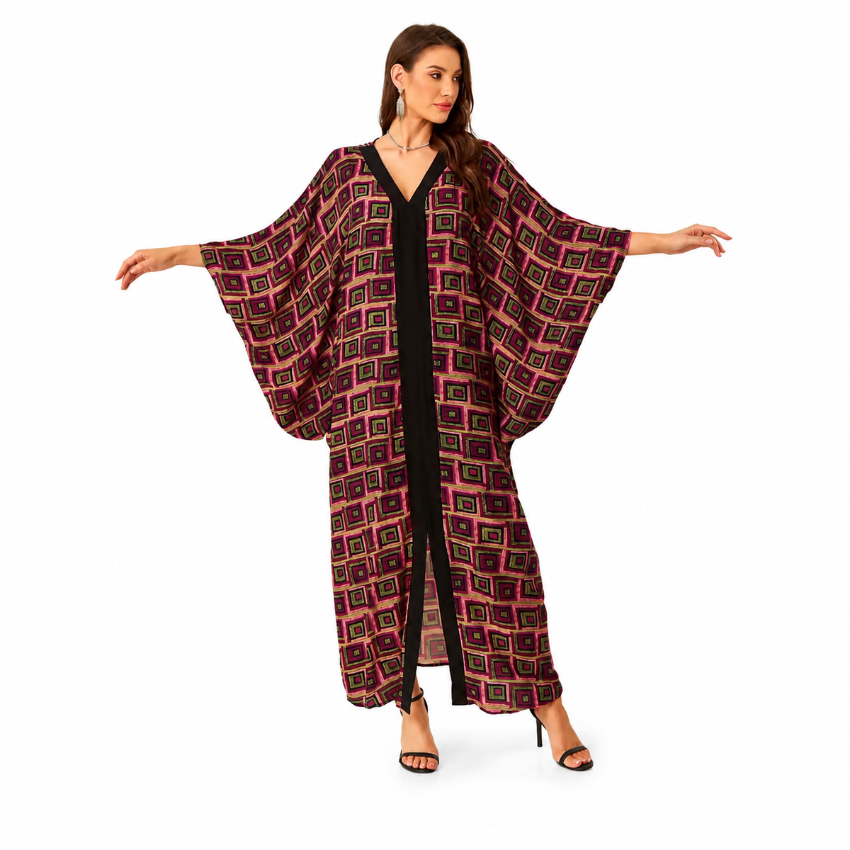 A woman modeling a long, flowy kaftan-style cover-up with wide sleeves and a geometric print in dark red, black, and gold, worn over a black jumpsuit against a plain white background.