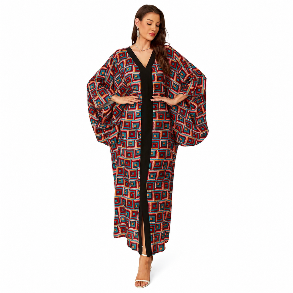 A woman modeling a long, loose kaftan-style cover-up with a geometric multicolor pattern over a black dress, set against a plain white studio background.