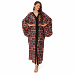 A woman modeling a long, loose kaftan-style cover-up with a geometric multicolor pattern over a black dress, set against a plain white studio background.