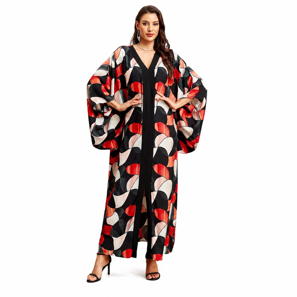 A woman modeling a long, loose maxi dress with wide balloon sleeves and a bold abstract geometric print in black, red, beige, and white, set against a plain white background.