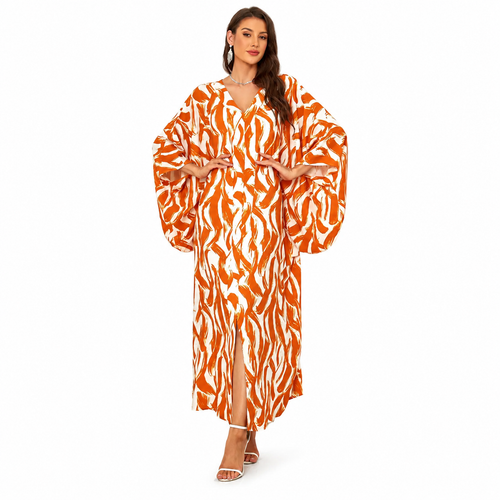 A woman modeling a long orange and white tiger-print kaftan dress with voluminous bell sleeves and a front slit, photographed against a plain white studio background.