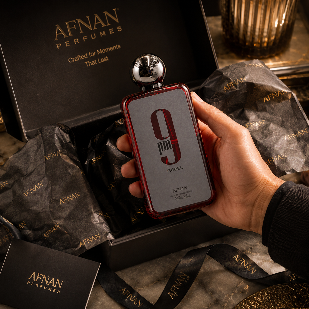 Afnan 9PM Rebel perfume being presented from premium gift box with luxury tissue paper and elegant unboxing presentation.