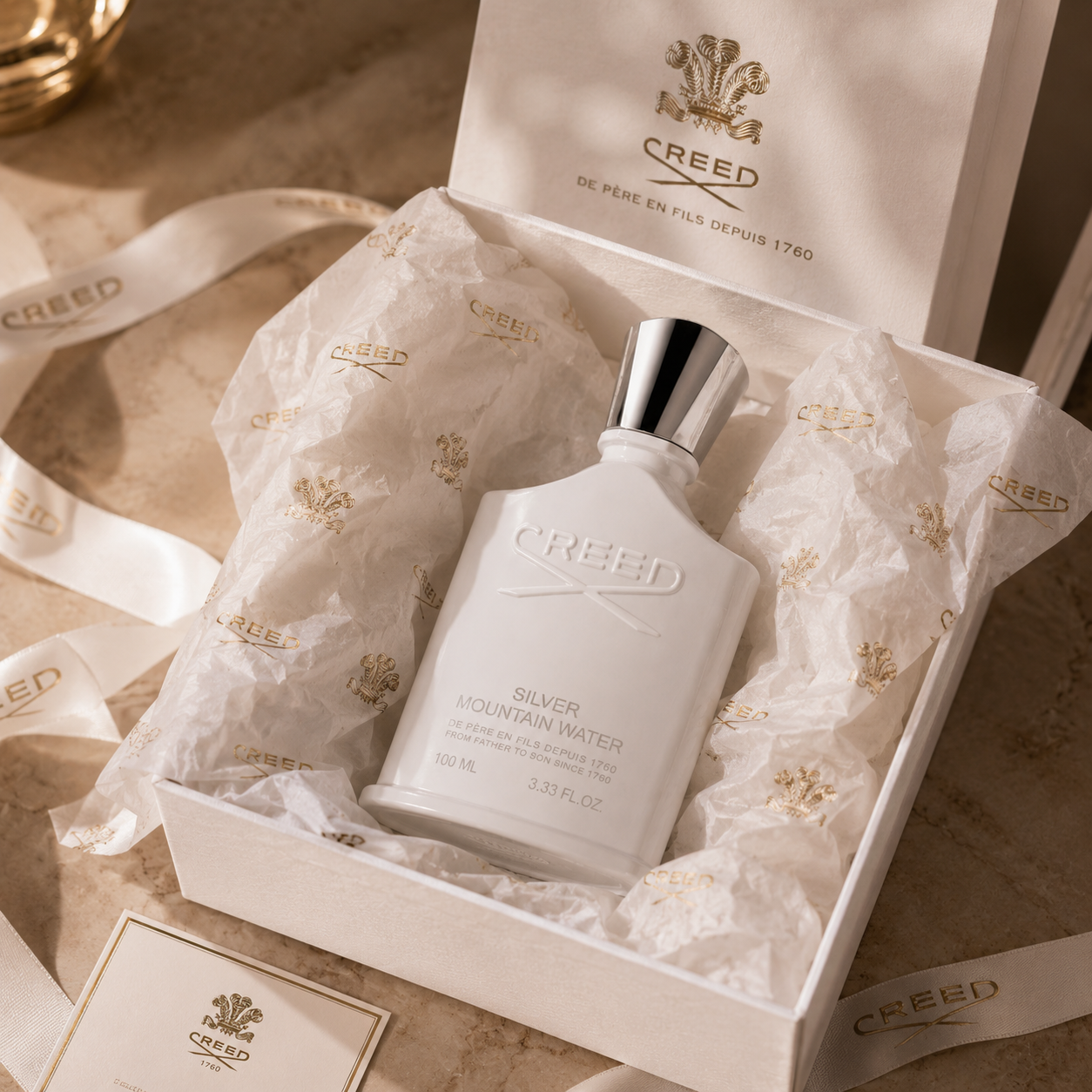 Luxury unboxing presentation of Creed Silver Mountain Water perfume with premium tissue paper and elegant gift packaging