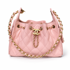 A light pink quilted leather shoulder bag with gold-tone hardware, featuring a prominent interlocking CC logo on a chain strap and a matching chain draped across the front, set against a plain white background.
