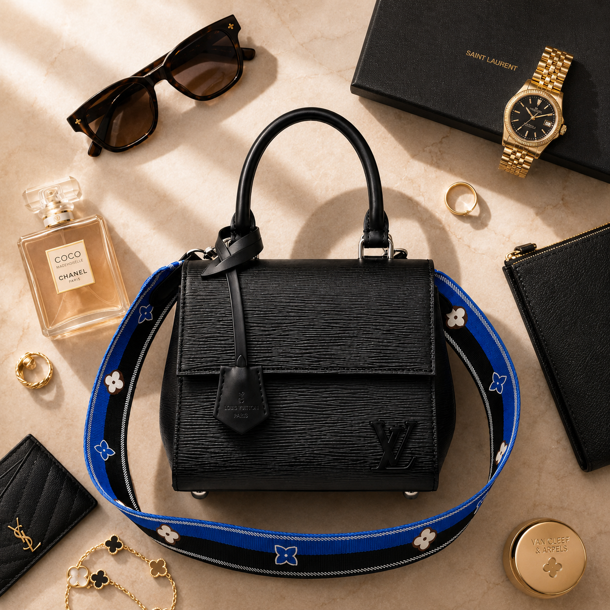 Luxury black handbag styled on marble surface with elegant accessories and soft beige tones