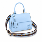 Elegant sky blue luxury women’s handbag with structured top handle and designer shoulder strap on white background.