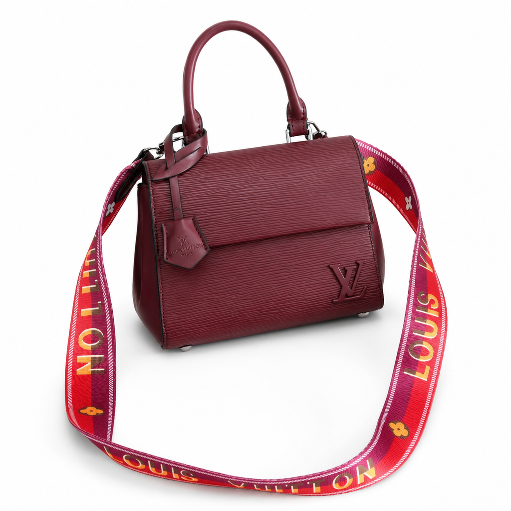 Luxury burgundy textured handbag with structured top handle and designer-inspired shoulder strap on clean white background.