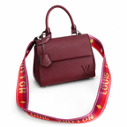 Luxury burgundy textured handbag with structured top handle and designer-inspired shoulder strap on clean white background.