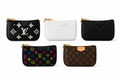 Luxury women's monogram wristlet pouch with premium textured finish and gold zipper on a white background.
