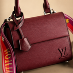 Maroon handbag with visible Louis Vuitton logo on a beige background