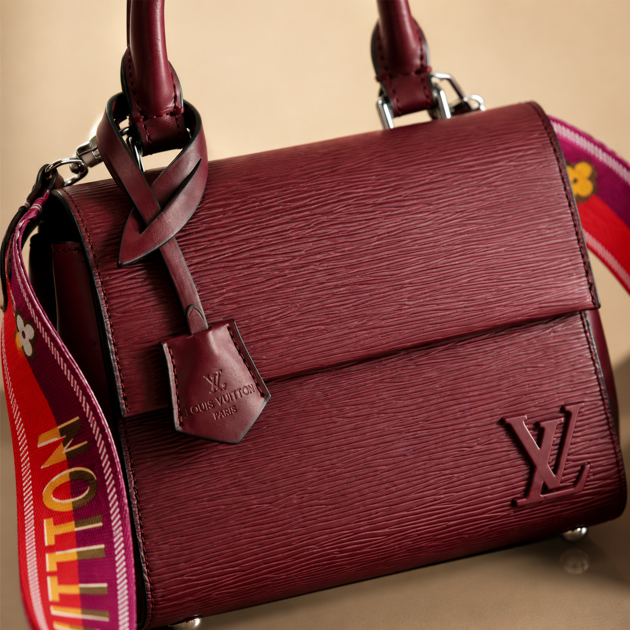 Maroon handbag with visible Louis Vuitton logo on a beige background