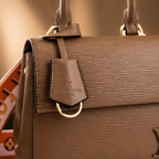Close-up of luxury textured leather handbag showing premium stitching, gold hardware, and elegant craftsmanship.