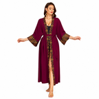 A woman modeling a long, deep burgundy maxi robe with wide sleeves and gold geometric patterned trim along the front opening and cuffs, shown against a plain white background.
