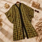 A loose, open-front kimono-style robe with a geometric multicolor print on a beige background, styled in a flat-lay with a gold handbag, sunglasses, jewelry, and a beige scarf on a marble surface.